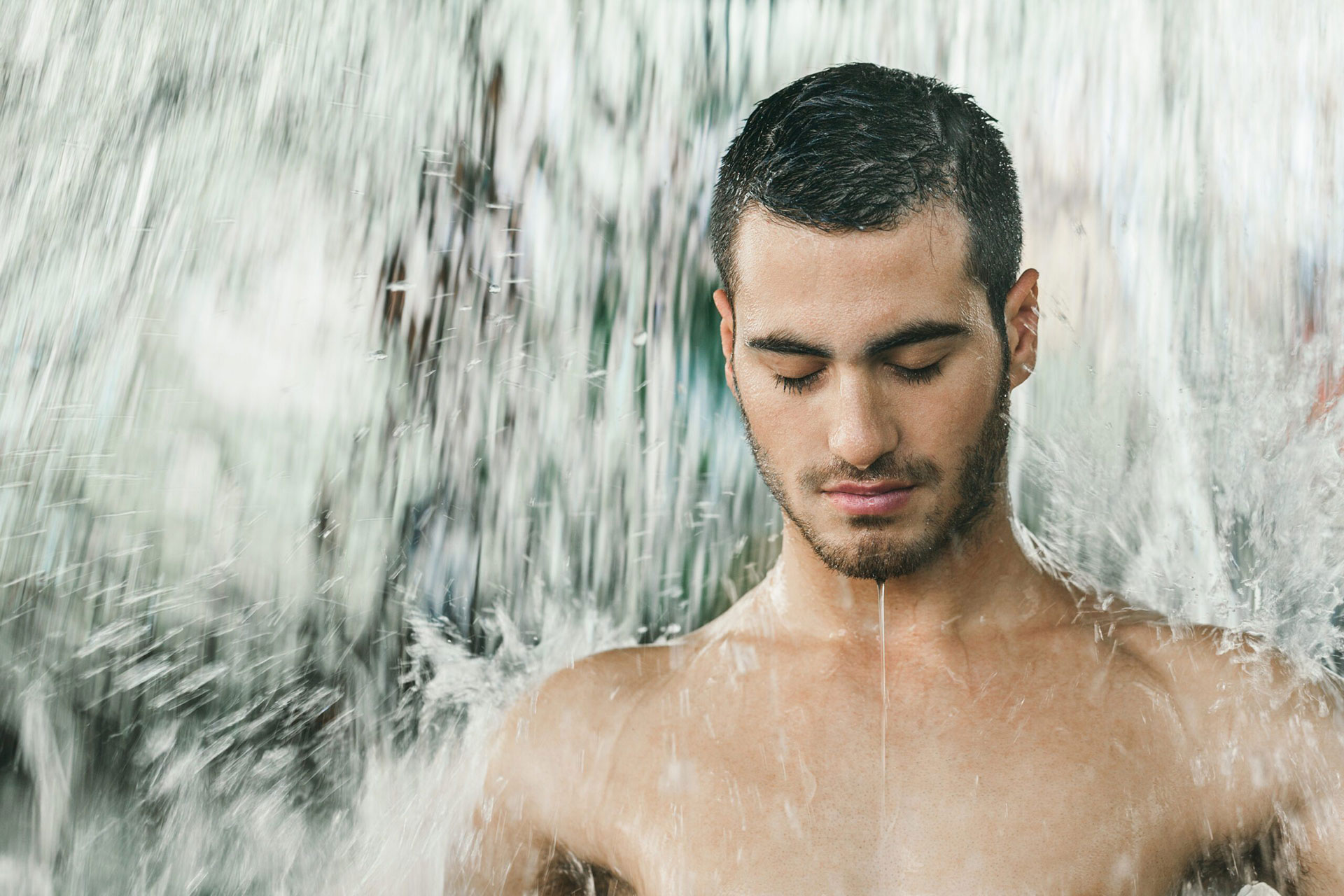 Man with eyes closed with water cascading over his body